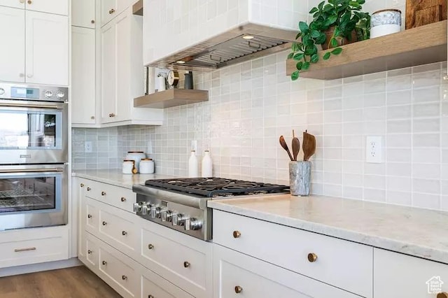 5359 S Pura Cir Unit 142, St George, UT 84790 - kitchen featuring custom exhaust hood, decorative backsplash, appliances with stainless steel finishes, light stone counters, and white cabinetry
