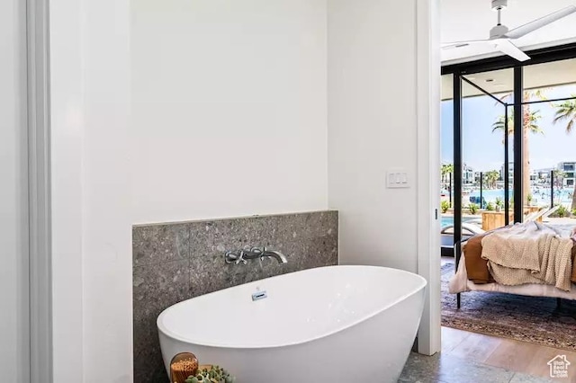 5359 S Pura Cir Unit 142, St George, UT 84790 - bathroom featuring a tub to relax in, ceiling fan, hardwood / wood-style flooring, and a wall of windows