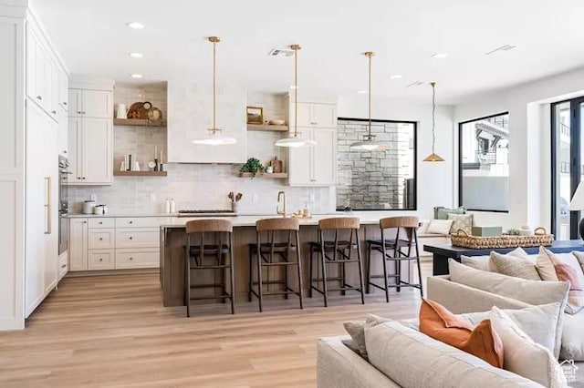5359 S Pura Cir Unit 142, St George, UT 84790 - kitchen with white cabinets, a breakfast bar, hanging light fixtures, and an island with sink
