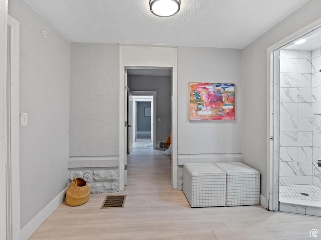 hallway with a textured ceiling and light wood-type flooring