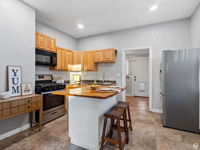 kitchen with decorative backsplash, appliances with stainless steel finishes, butcher block countertops, a kitchen island, and a kitchen bar