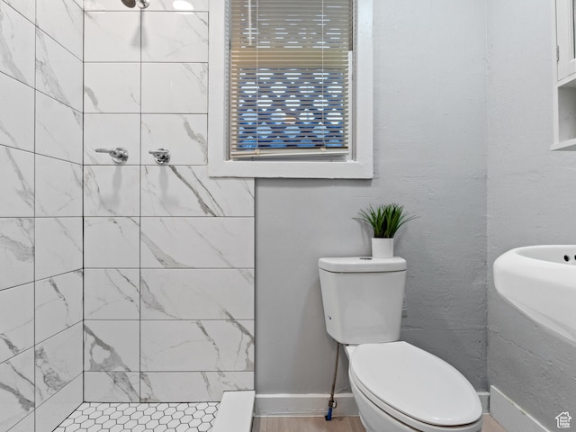bathroom featuring tiled shower and toilet