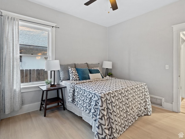 bedroom featuring ceiling fan, light hardwood / wood-style floors, and multiple windows