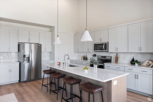 kitchen featuring decorative light fixtures, stainless steel appliances, white cabinetry, and sink