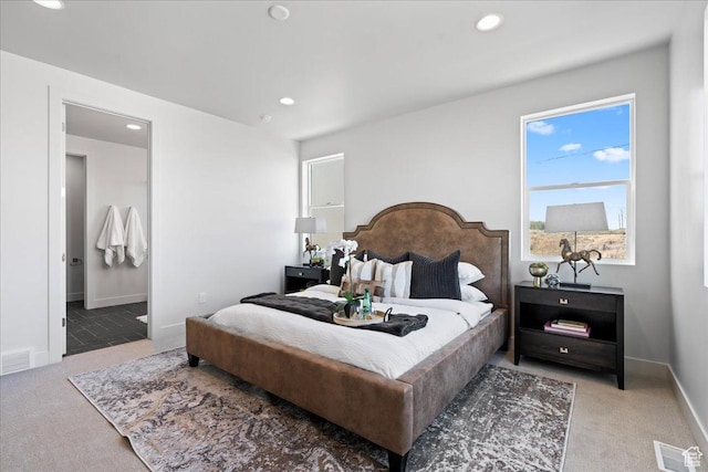 bedroom with light colored carpet and ensuite bath