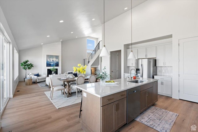 kitchen featuring appliances with stainless steel finishes, backsplash, decorative light fixtures, white cabinets, and plenty of natural light