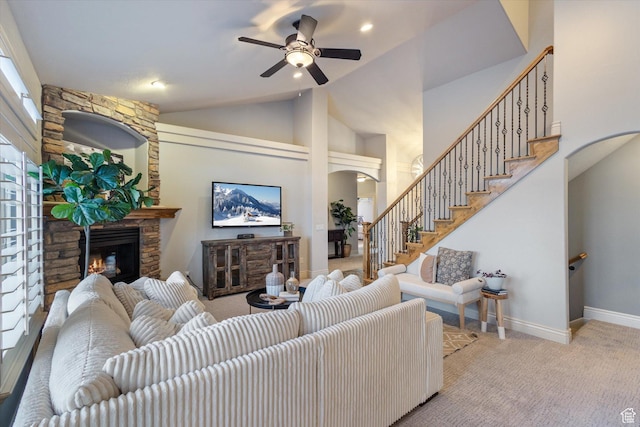 living room with a stone fireplace, ceiling fan, light carpet, and vaulted ceiling