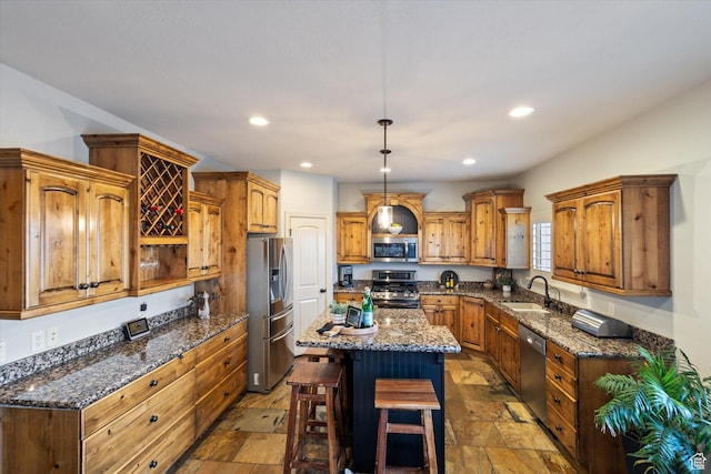 kitchen with dark stone countertops, a kitchen island, sink, and stainless steel appliances