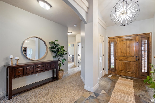 carpeted entrance foyer with an inviting chandelier