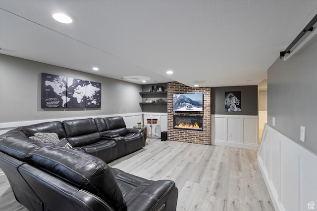 living room with a fireplace, light wood-type flooring, and a barn door