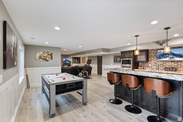 rec room featuring light wood-type flooring and bar