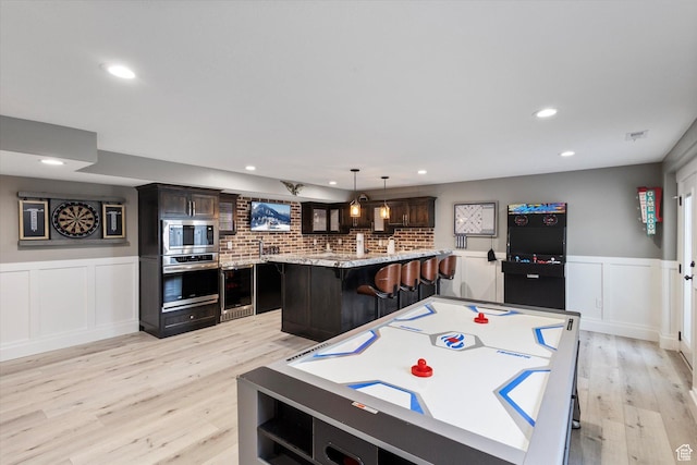 game room with wine cooler and light hardwood / wood-style flooring
