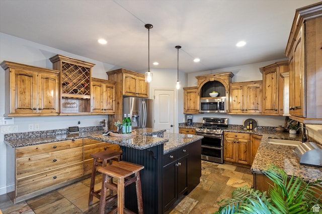 kitchen with dark stone countertops, pendant lighting, a kitchen island, and stainless steel appliances