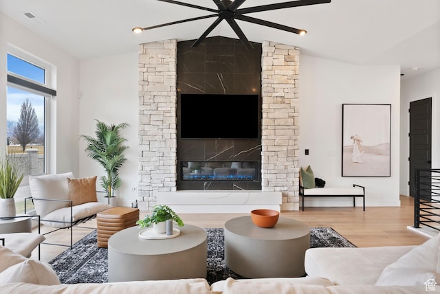 living room with lofted ceiling, a fireplace, and light hardwood / wood-style flooring