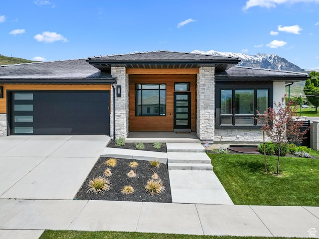 1302 N 750 E, Orem, UT 84097 - view of front of home featuring stone siding, a mountain view, an attached garage, driveway, and a front yard