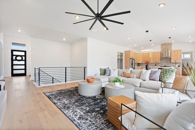 living room with ceiling fan, light hardwood / wood-style flooring, and lofted ceiling