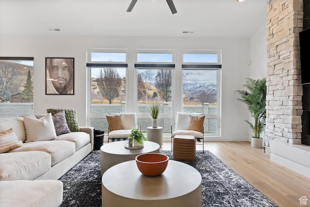 living room with a fireplace, light hardwood / wood-style floors, and ceiling fan