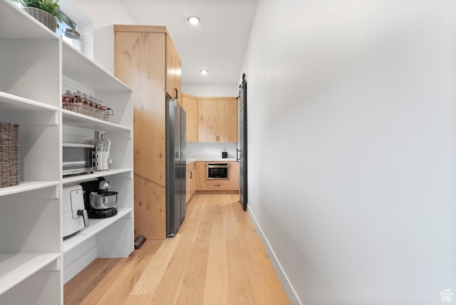 hallway with a barn door and light wood-type flooring