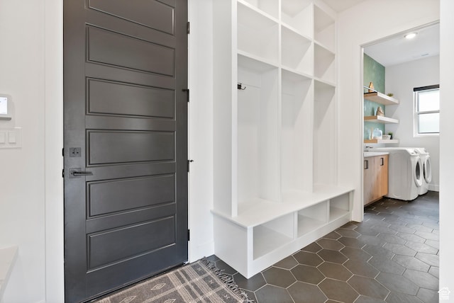 mudroom with dark tile patterned floors and washing machine and clothes dryer