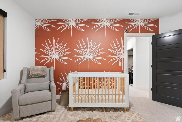 unfurnished bedroom with light colored carpet and a nursery area