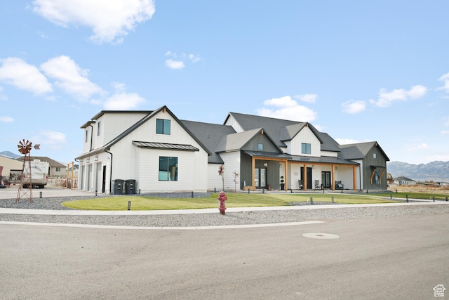 modern farmhouse with a front yard, a mountain view, and a garage
