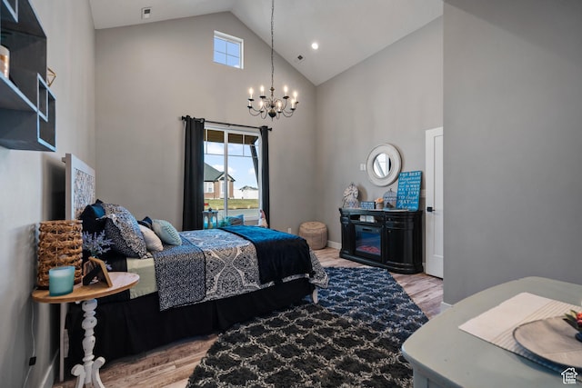 bedroom featuring light wood-type flooring, high vaulted ceiling, and a notable chandelier