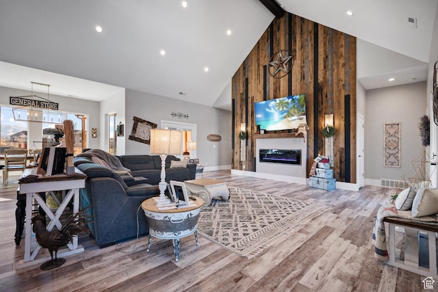 living room featuring beam ceiling, light hardwood / wood-style floors, and high vaulted ceiling