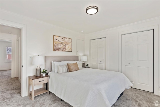 bedroom featuring crown molding, light colored carpet, and two closets