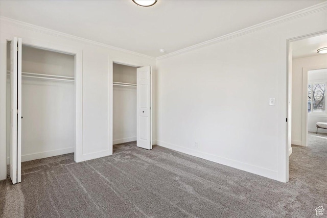 unfurnished bedroom with carpet, multiple closets, and crown molding