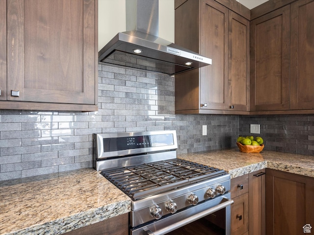 kitchen with backsplash, stainless steel gas stove, and wall chimney exhaust hood