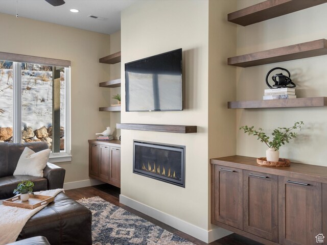 living room with dark wood-style flooring, visible vents, baseboards, a glass covered fireplace, and recessed lighting