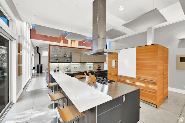 1762 E Millcreek Way, Millcreek, UT 84106 - kitchen with modern cabinets, island range hood, backsplash, a kitchen breakfast bar, and stainless steel gas cooktop