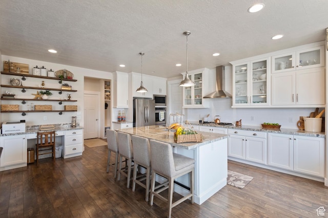 536 W Granite Cir, Saratoga Springs, UT 84045 - kitchen featuring white cabinets, open shelves, appliances with stainless steel finishes, wall chimney exhaust hood, and a kitchen bar