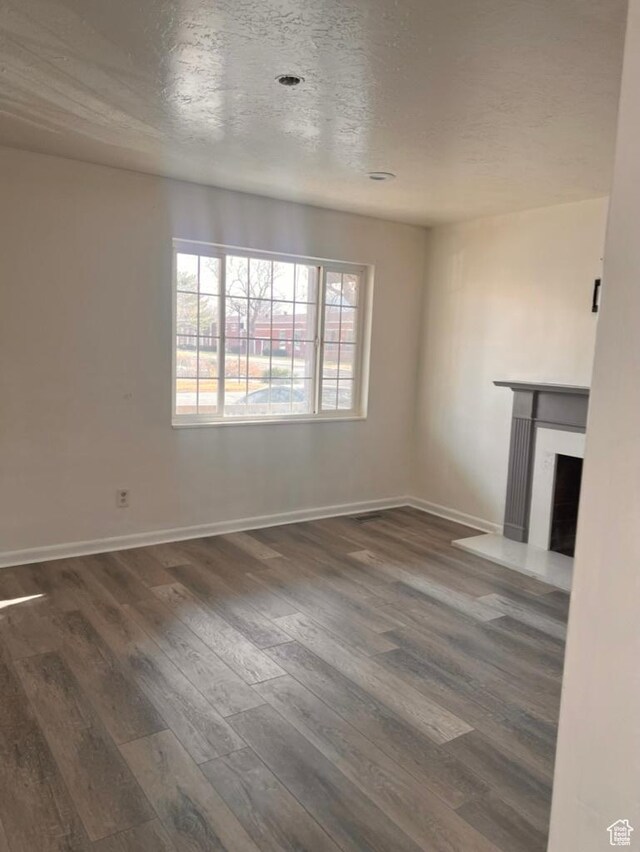 793 N 1200 W, Salt Lake City, UT 84116 - unfurnished living room featuring a textured ceiling, a fireplace with raised hearth, dark wood finished floors, and baseboards
