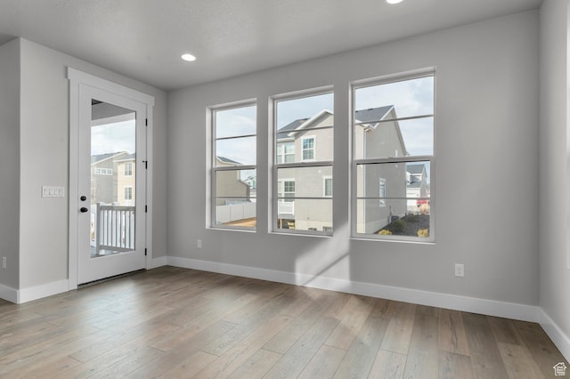interior space with plenty of natural light, wood finished floors, and baseboards