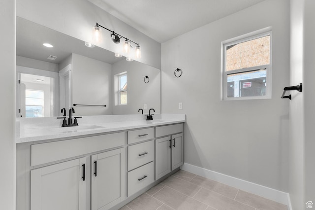 full bath featuring visible vents, baseboards, double vanity, a sink, and tile patterned floors