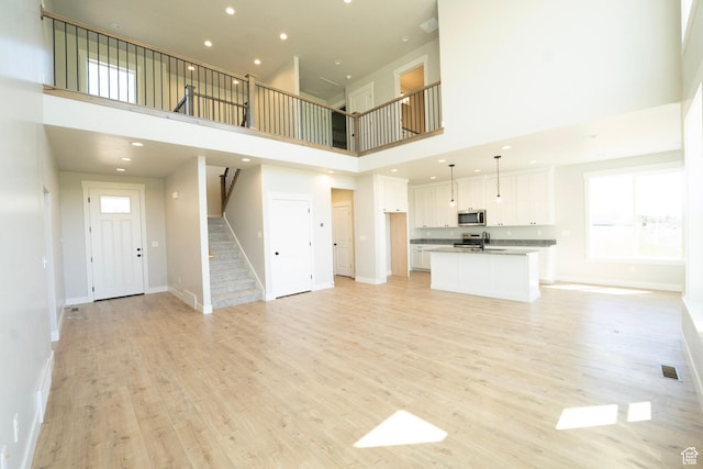 573 N 510 E Unit 20, Smithfield, UT 84335 - unfurnished living room with a towering ceiling, stairway, light wood-style flooring, baseboards, and recessed lighting