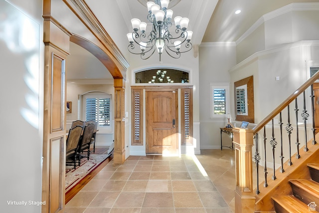 tiled foyer entrance with a notable chandelier, a high ceiling, and crown molding
