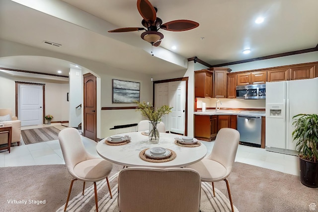 dining room with sink, light carpet, and ceiling fan