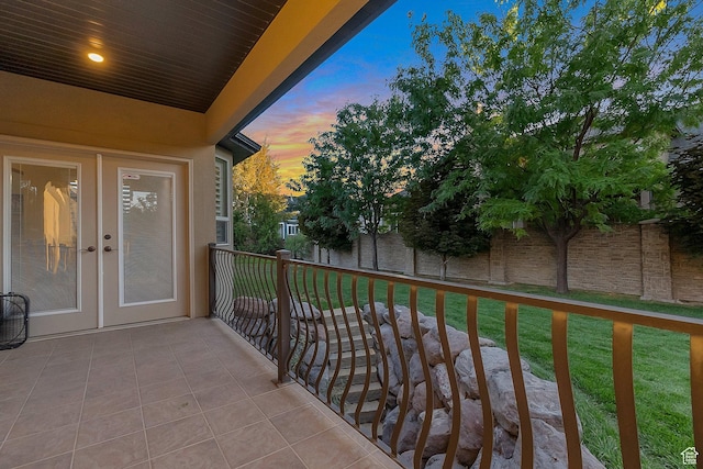 balcony at dusk with a patio area and french doors
