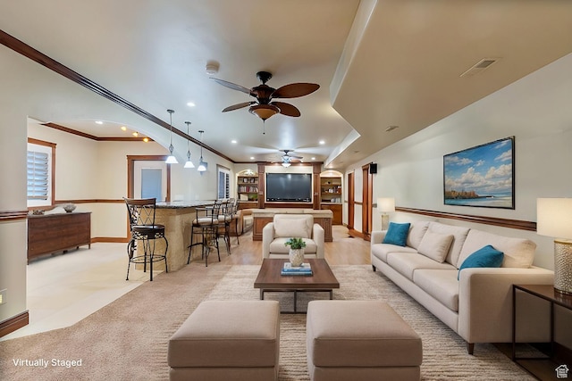 carpeted living room featuring ceiling fan and crown molding