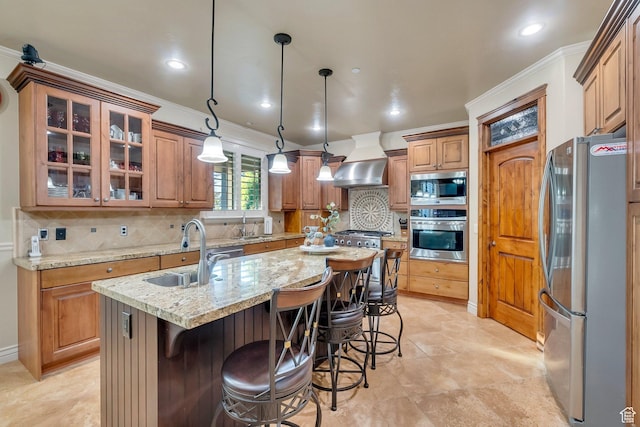 kitchen with appliances with stainless steel finishes, sink, extractor fan, pendant lighting, and a kitchen island with sink