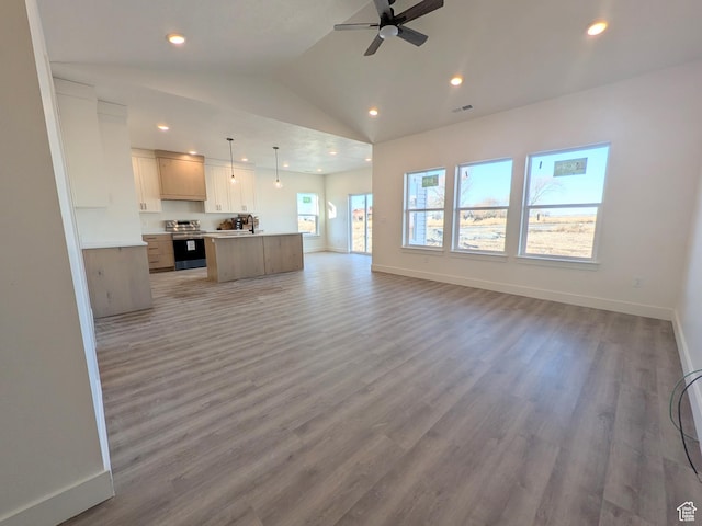 unfurnished living room with hardwood / wood-style flooring, vaulted ceiling, ceiling fan, and sink