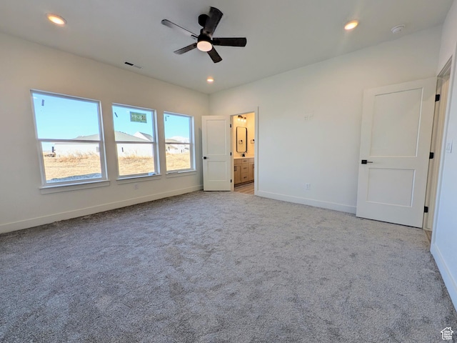 unfurnished bedroom with connected bathroom, light colored carpet, and ceiling fan