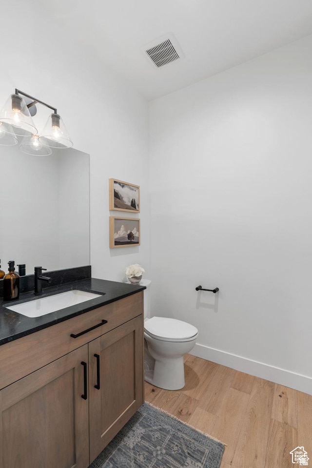 bathroom featuring vanity, wood-type flooring, and toilet