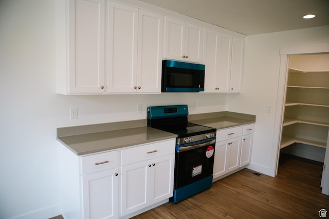 kitchen with electric range, white cabinets, and dark hardwood / wood-style floors