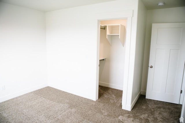 unfurnished bedroom featuring a walk in closet, carpet floors, and a closet