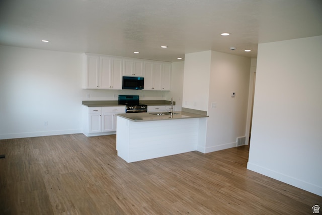 kitchen with white cabinetry, sink, black range with electric cooktop, kitchen peninsula, and light wood-type flooring