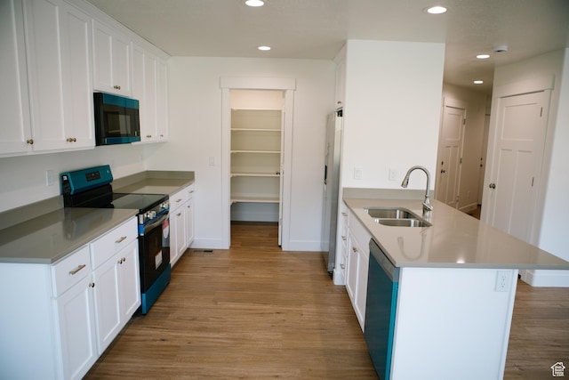 kitchen featuring white cabinets, sink, light hardwood / wood-style flooring, and black appliances