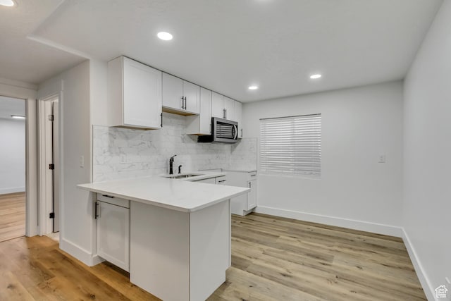 12756 S Diamond Back Dr W, Riverton, UT 84096 - kitchen featuring sink, white cabinetry, decorative backsplash, light hardwood / wood-style floors, and kitchen peninsula